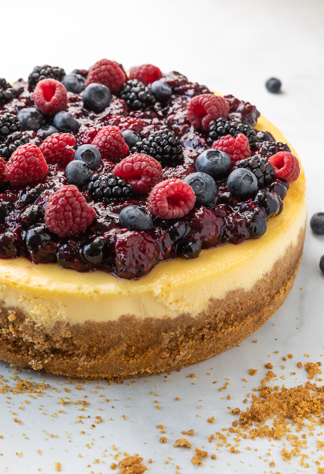 Ricotta cheesecake topped with whole fresh berries and a berry sauce.