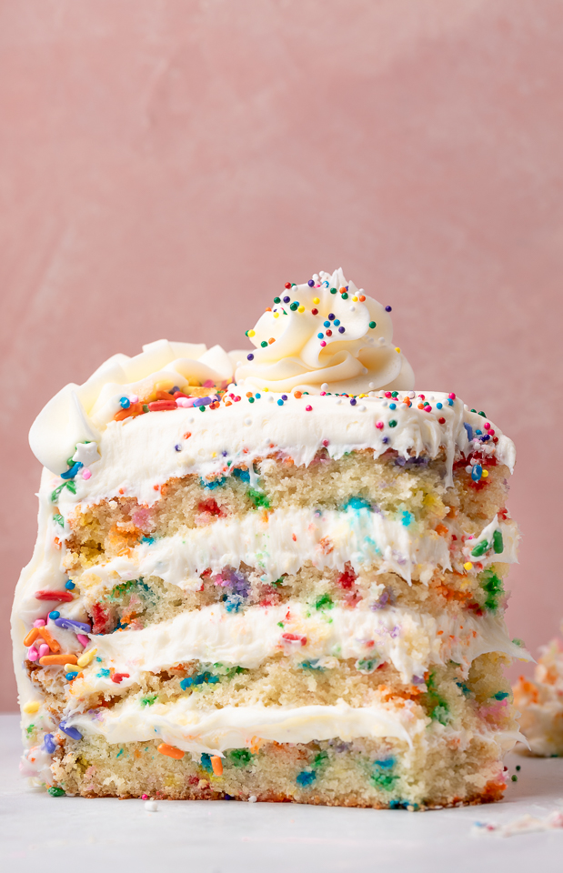 Slice of funfetti cake with a bite taken out of it.