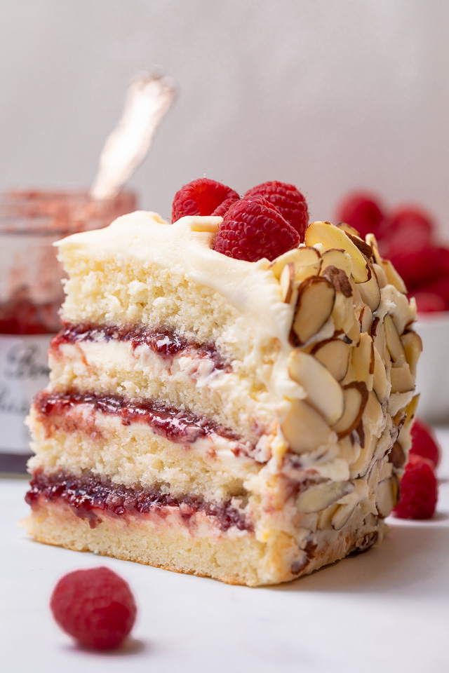 This Almond Raspberry Cake with White Chocolate Amaretto Buttercream Frosting is a total showstopper! Featuring four layers of light and fluffy almond cake, raspberry filling, and creamy white chocolate amaretto cream, this cake is decadently sweet! A must try if you love raspberry almond desserts!