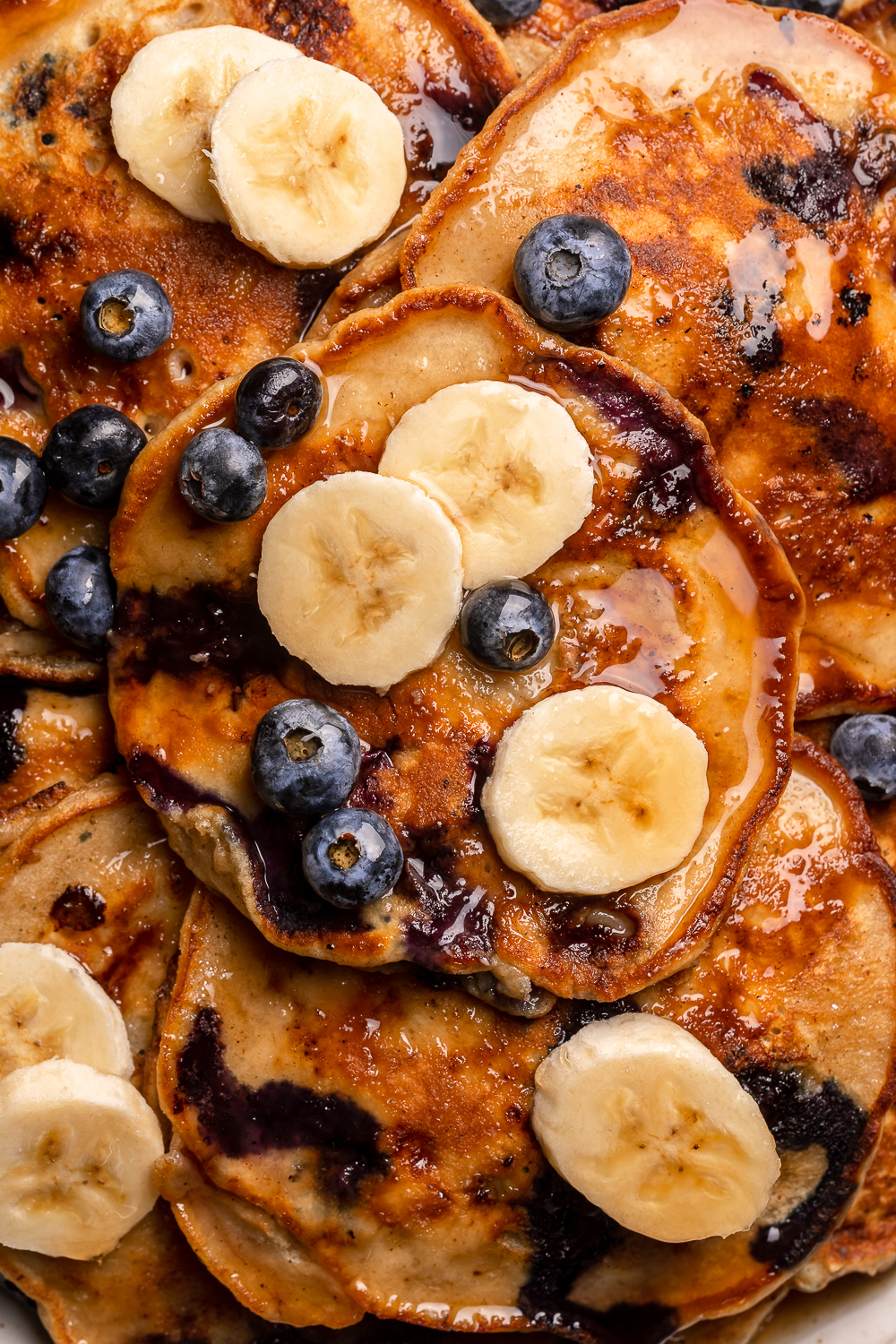 Ripe bananas and fresh blueberries make these Banana Blueberry Pancakes tender, fluffy, and flavorful! The pancake batter comes together in just minutes, and is quickly cooked to golden brown on a hot skillet. Top with maple syrup, extra blueberries, and banana slices for a beautiful breakfast at home!
