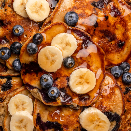 Ripe bananas and fresh blueberries make these Banana Blueberry Pancakes tender, fluffy, and flavorful! The pancake batter comes together in just minutes, and is quickly cooked to golden brown on a hot skillet. Top with maple syrup, extra blueberries, and banana slices for a beautiful breakfast at home!