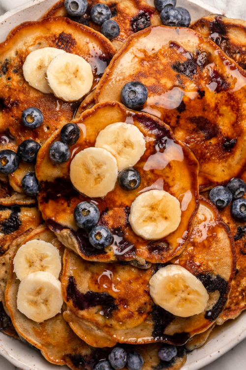 Ripe bananas and fresh blueberries make these Banana Blueberry Pancakes tender, fluffy, and flavorful! The pancake batter comes together in just minutes, and is quickly cooked to golden brown on a hot skillet. Top with maple syrup, extra blueberries, and banana slices for a beautiful breakfast at home!
