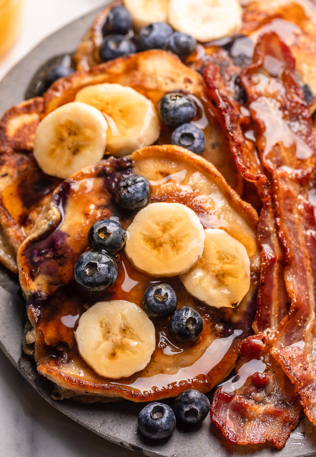 Ripe bananas and fresh blueberries make these Banana Blueberry Pancakes tender, fluffy, and flavorful! The pancake batter comes together in just minutes, and is quickly cooked to golden brown on a hot skillet. Top with maple syrup, extra blueberries, and banana slices for a beautiful breakfast at home!