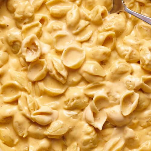 Mac and cheese with creamy cheese sauce in a skillet with a spoon.