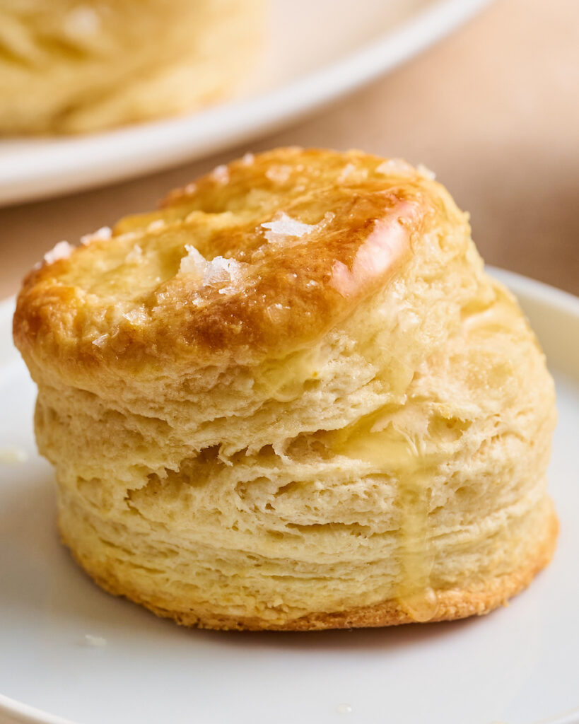 Flaky Golden Brown Buttermilk Biscuits on a white plate.