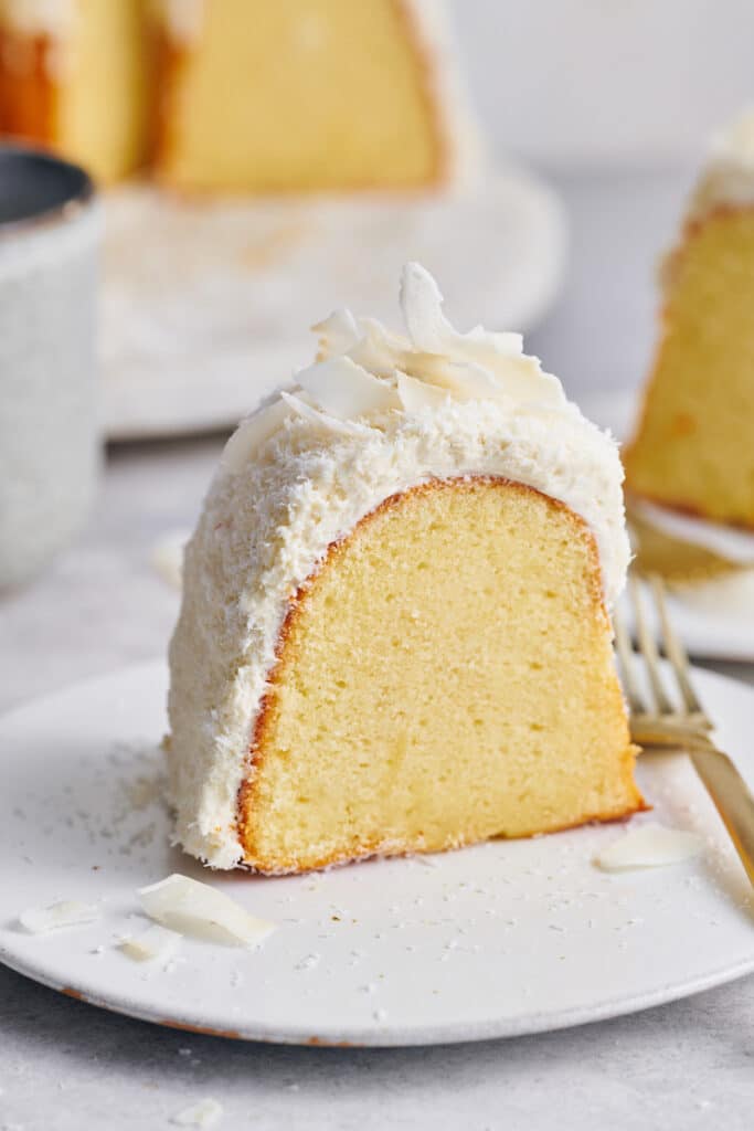 Slice of white chocolate coconut bundt cake on a dessert plate with a small fork. 