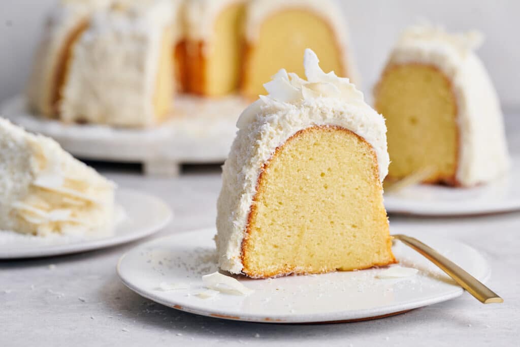 Slice of white chocolate bundt cake on a white plate.