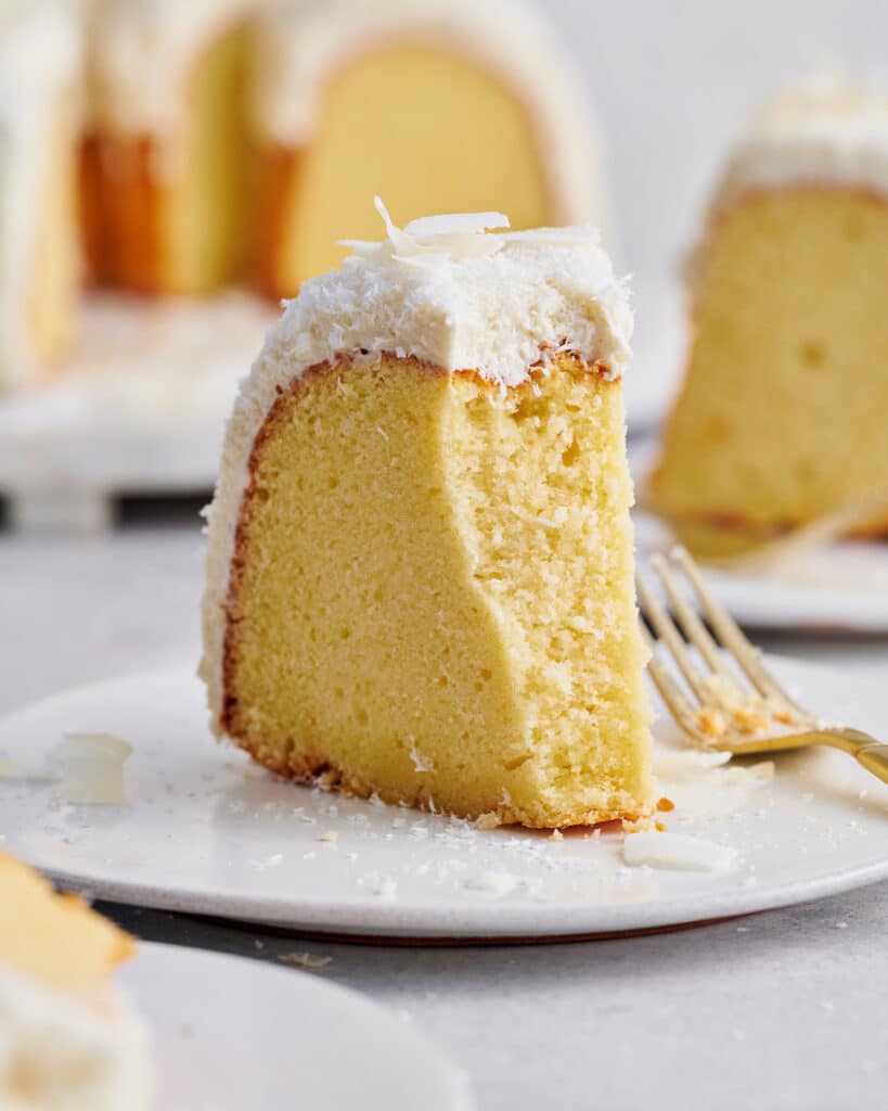Slice of white chocolate coconut bundt cake with a bite taken out.
