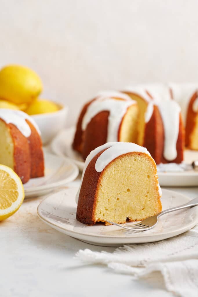 Slice of lemon bundt cake on white plate a bite taken out of the cake.