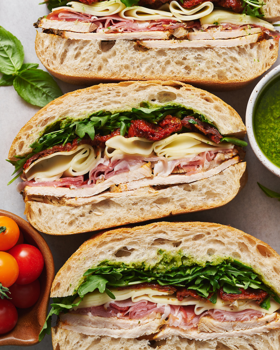 This crowd-pleasing Italian Turkey Club Sandwich is perfect for picnics, parties, or those nights it's just too hot to cook! Loaded with sliced turkey, prosciutto, arugula, sun-dried tomatoes, and a homemade Italian dressing, this recipe is so flavorful and fresh. So without further ado, let's make sandwiches!
