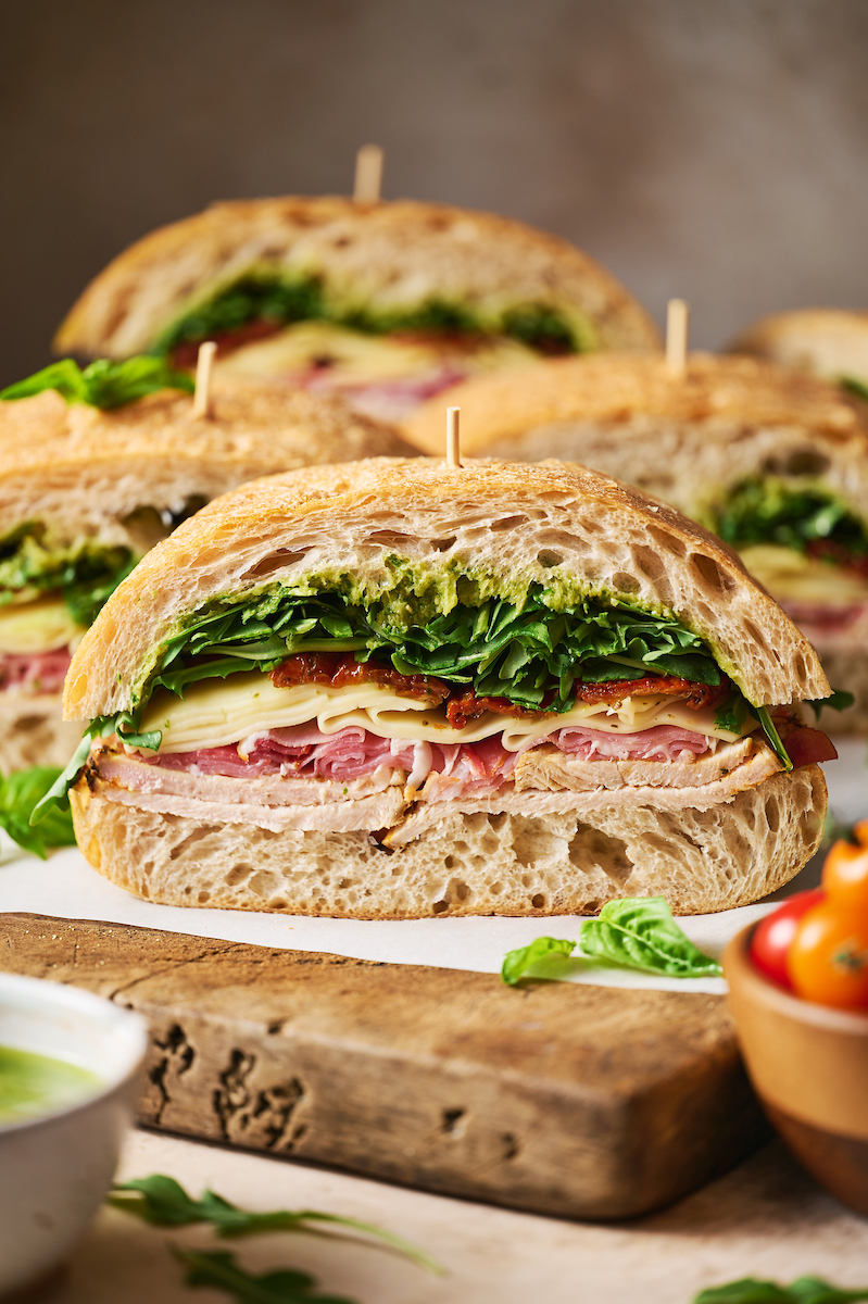 Club sandwich showing layers of arugula, sun-dried tomatoes, and turkey.