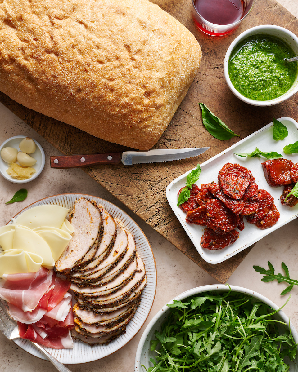 Ingredients for a turkey club sandwich on a large wooden cutting board.