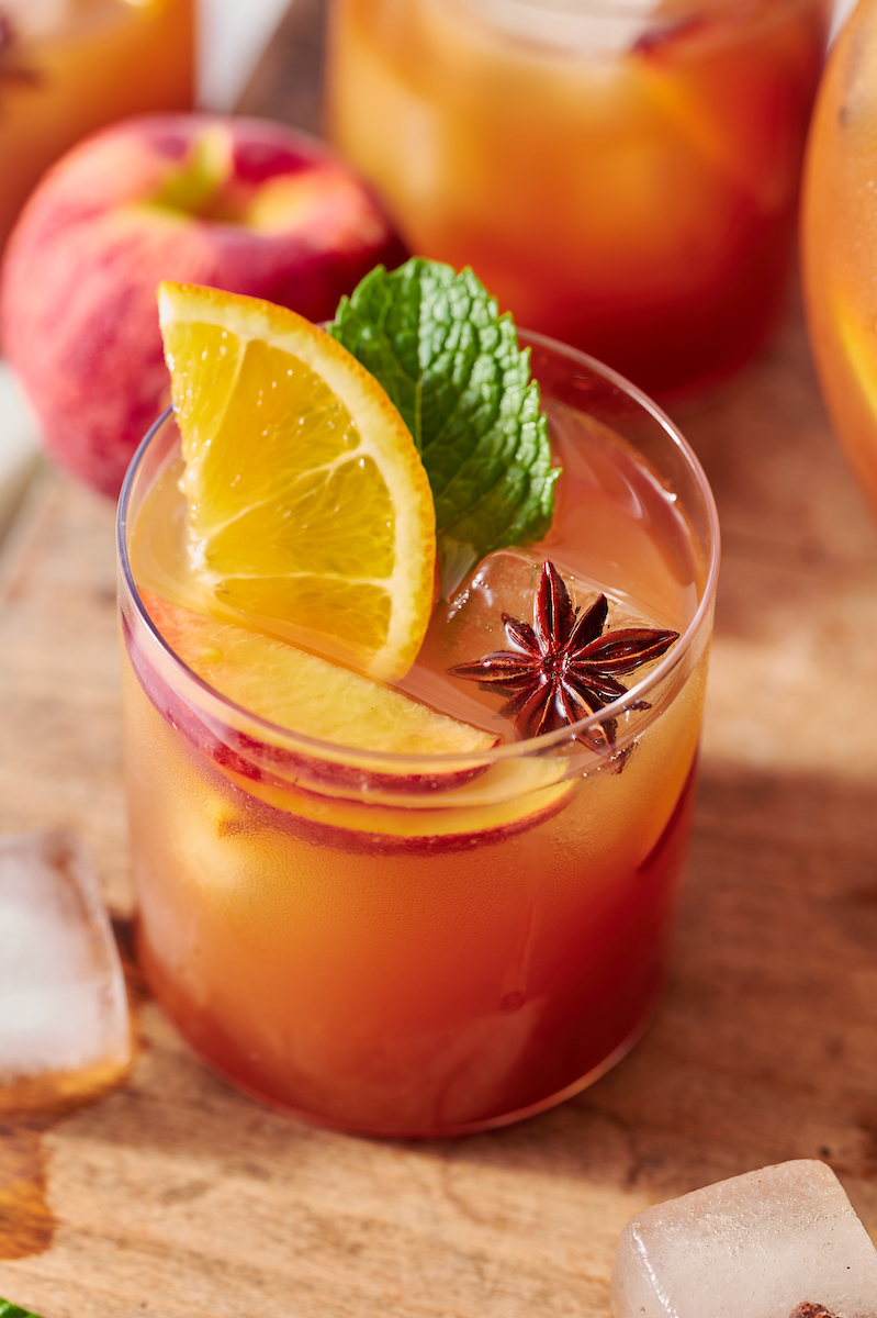 If you're searching for a big batch summer cocktail, look no further than this bourbon spiked peach iced tea! Made with peach nectar, black tea, and fresh peach slices, this recipe is perfect for barbecues, parties, and picnics. Bust out a large pitcher and make a batch today!