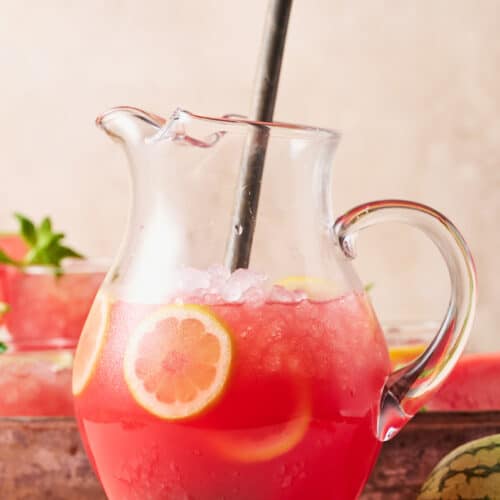 Pitcher full of watermelon lemonade with stirring spoon.