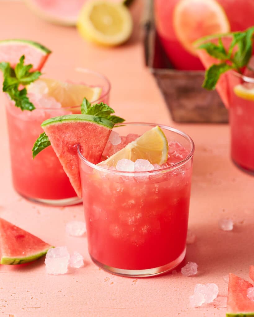 Three glasses filled with ice cubes and watermelon lemonade.