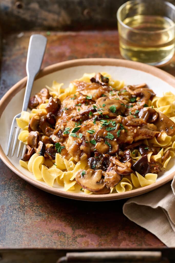 Plate of chicken marsala over buttered noodles.