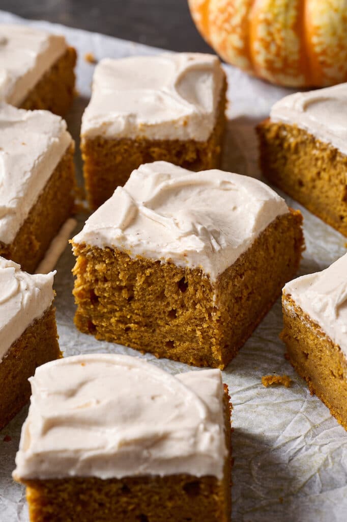 Pumpkin Cake sliced into squares on a piece of parchment paper.