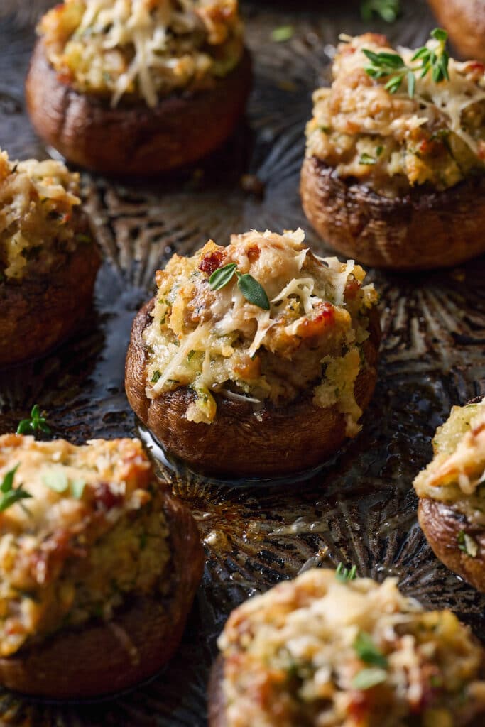 Stuffed mushrooms topped with Parmesan cheese on a baking sheet.