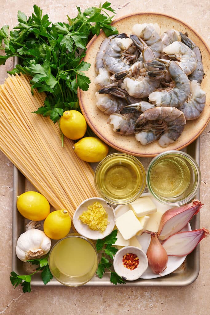 Ingredients for shrimp scampi recipe on a large baking sheet.