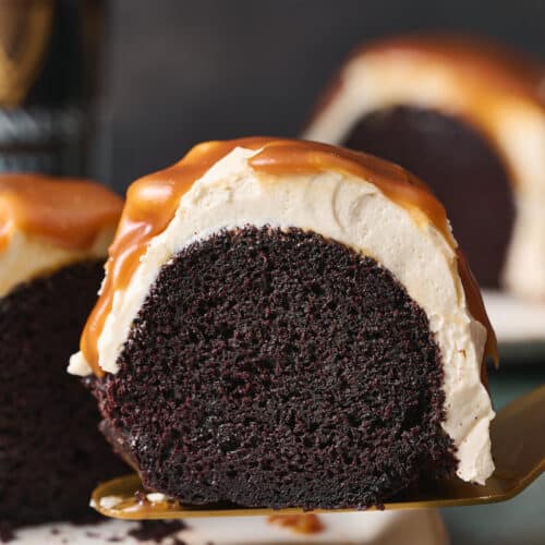 Slice of Guinness chocolate cake being lifted off cake stand with cake server.