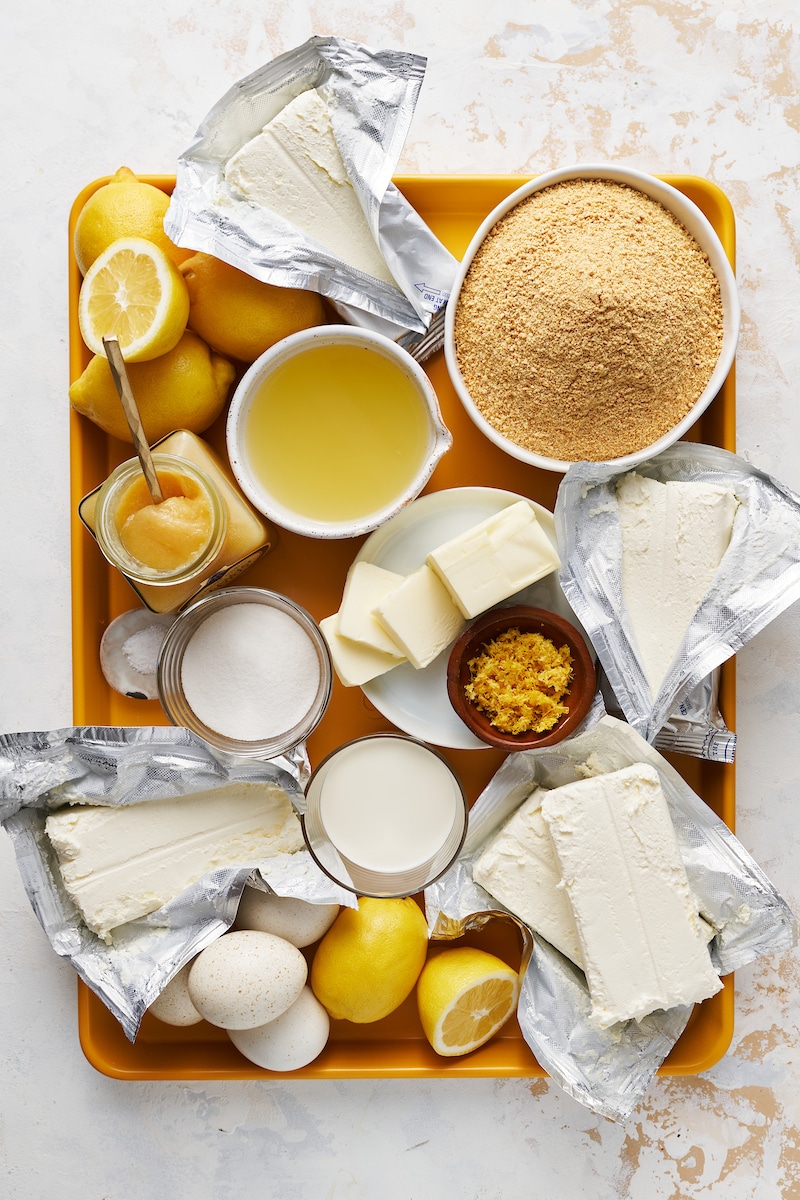 Ingredients for lemon cheesecake on a yellow tray.