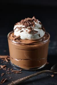 Small dish of chocolate mousse topped with whipped cream and chocolate shavings.