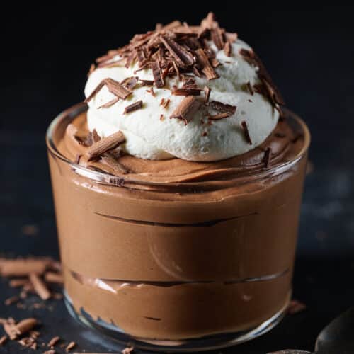 Small dish of chocolate mousse topped with whipped cream and chocolate shavings.