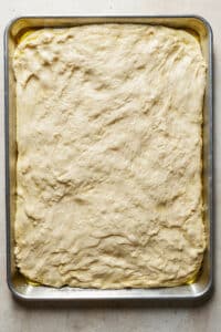 Homemade pizza crust pressed into pizza pan.