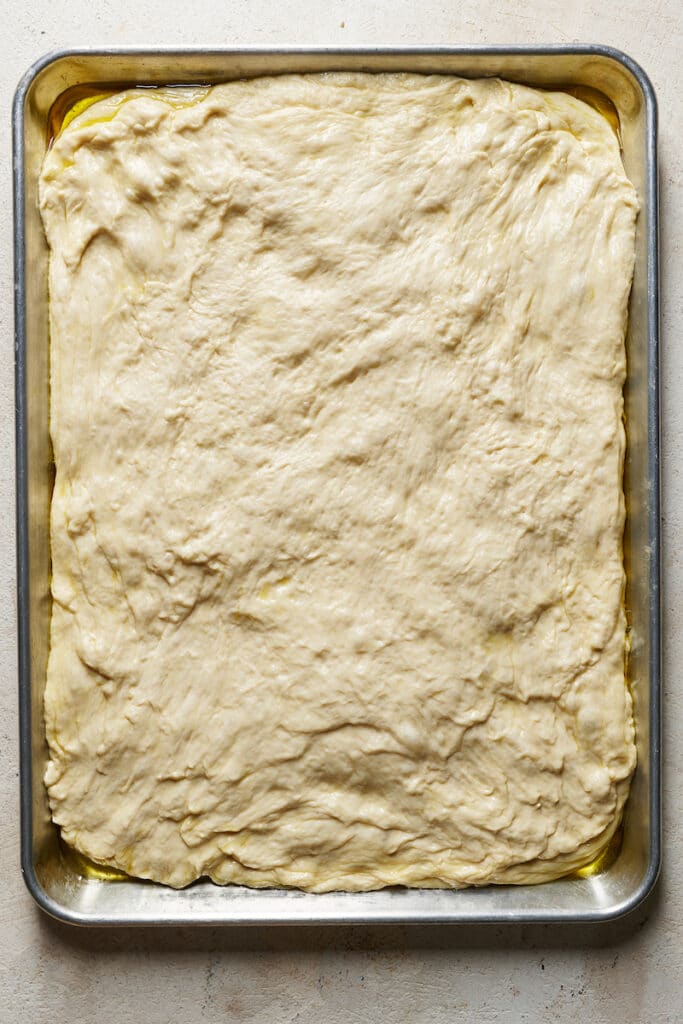 Homemade pizza crust pressed into pizza pan.