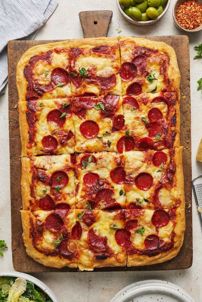 Pepperoni pizza on a wooden cutting board.