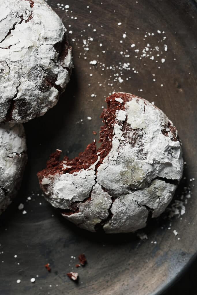A chocolate crinkle cookie with a bite taken out.