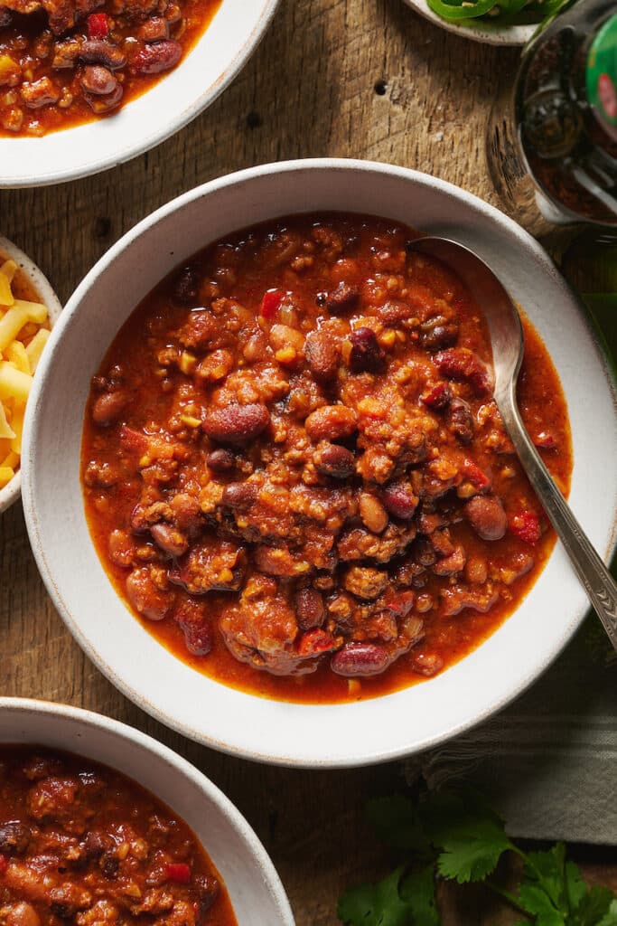 Bowl of beef and bean chili recipe in a white bowl with a spoon.