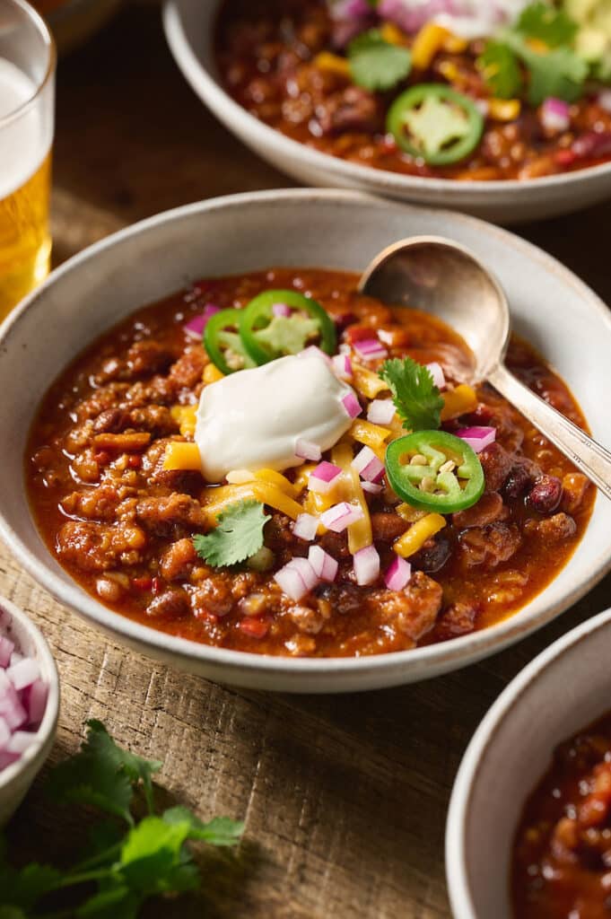 Bowl of chili with a spoon and topped with sour cream.
