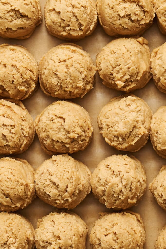 Balls of peanut butter cookie dough on a baking sheet.