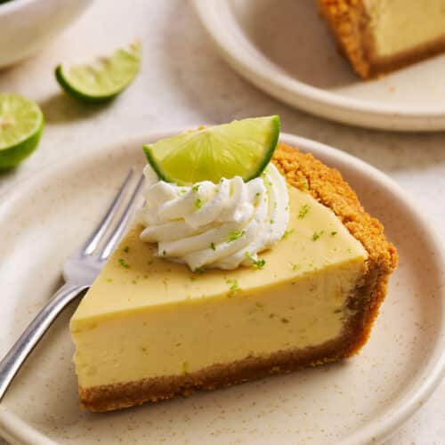 Slice of key lime pie on a plate with whipped cream on top.
