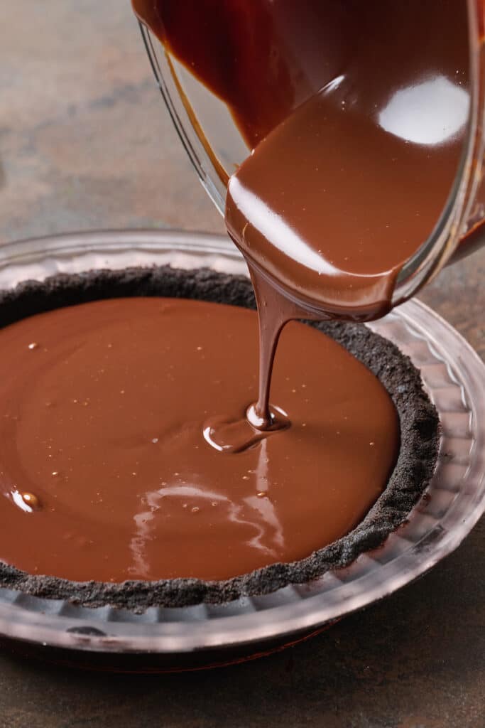 Chocolate cream pie filling being poured into oreo cookie crust.