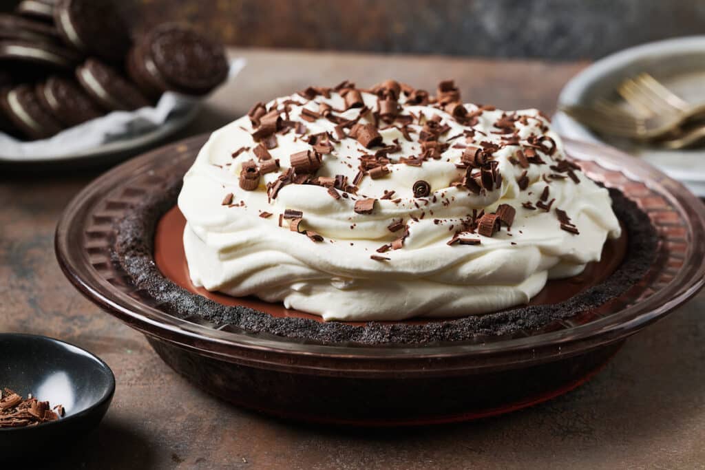 Chocolate cream pie in a baking dish with whipped cream on top.