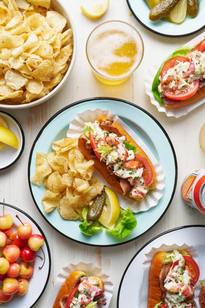 Learn how to make lobster rolls with this easy lobster roll recipe! The lobster salad contains cooked lobster meat, lemon juice, melted butter, mayo, and fresh herbs. The lobster mixture is piled high on toasted split top buns and topped with bacon, lettuce, and tomato! We love to serve these with crunchy potato chips and ice cold beer.