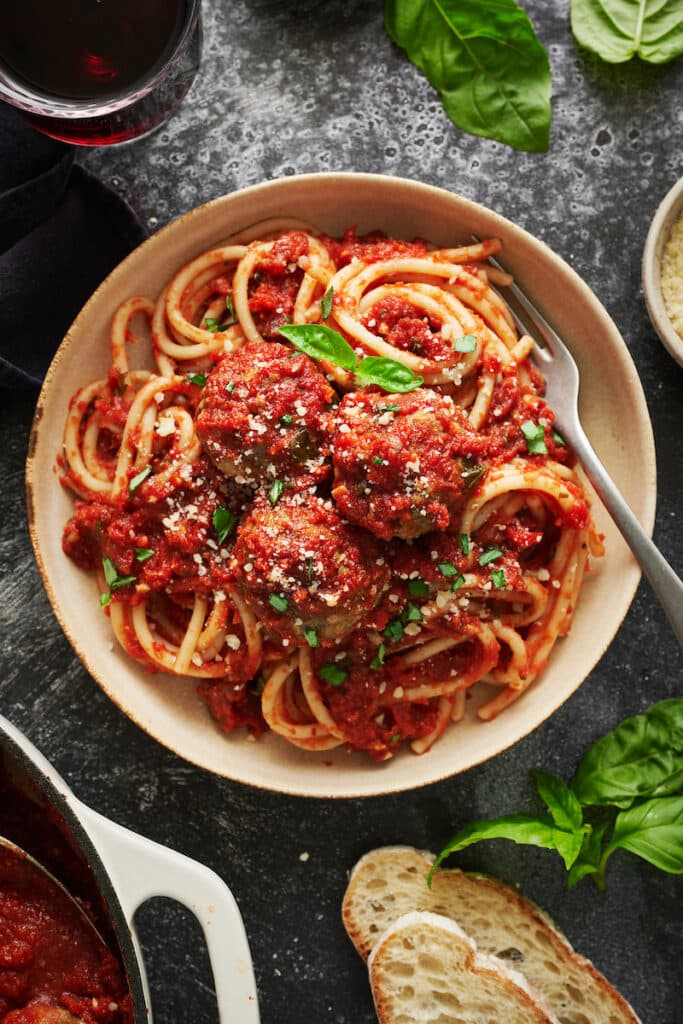 Meatballs with spaghetti and marinara sauce on a table.