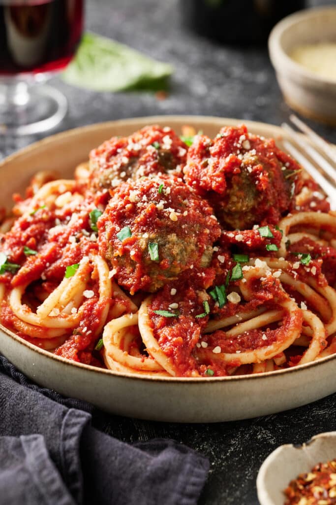 Meatballs with spaghetti and marinara sauce on a table.