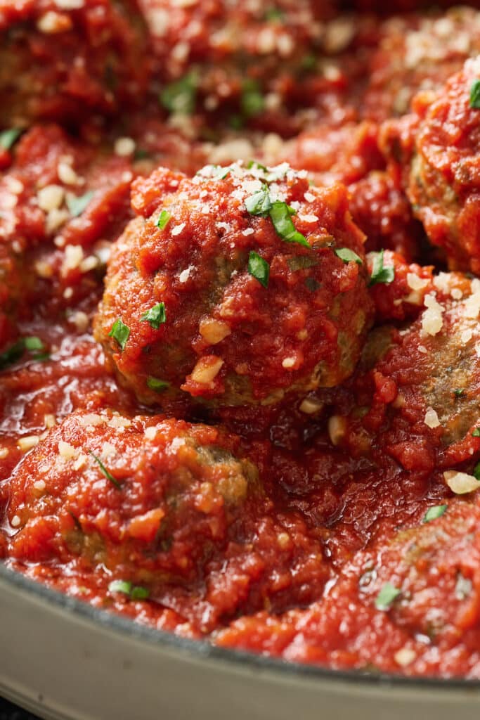 Meatballs in a pot with marinara sauce.