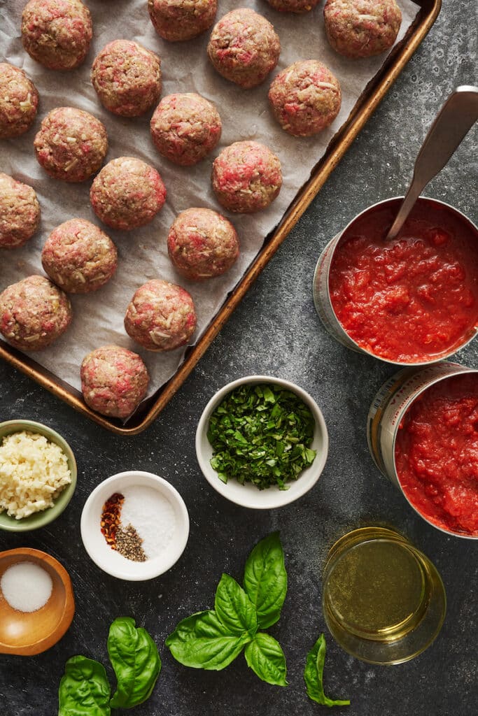 Ground beef raw meatballs on a baking sheet.