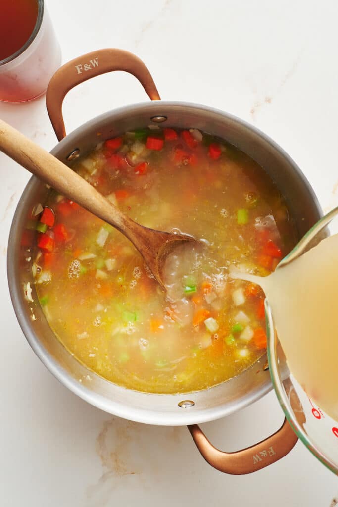 Pouring chicken broth into soup pot.