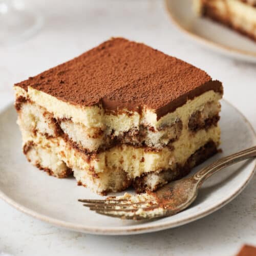Slice of tiramisu on a white dessert plate.