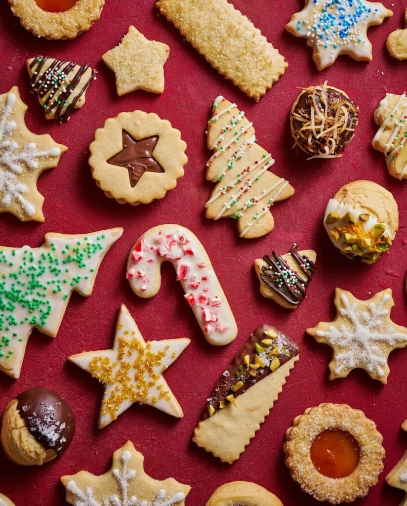 A variety of decorated Christmas cookies on a red table.