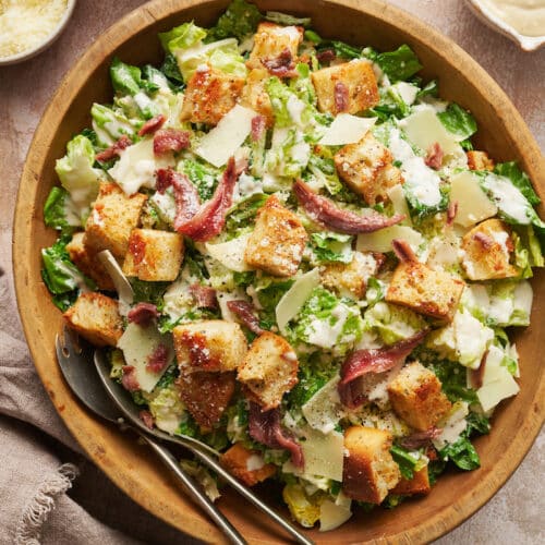 A big bowl of homemade Caesar salad topped with anchovies and croutons.