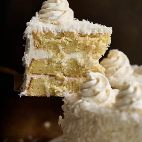 Slice of coconut cake being pulled from the platter.