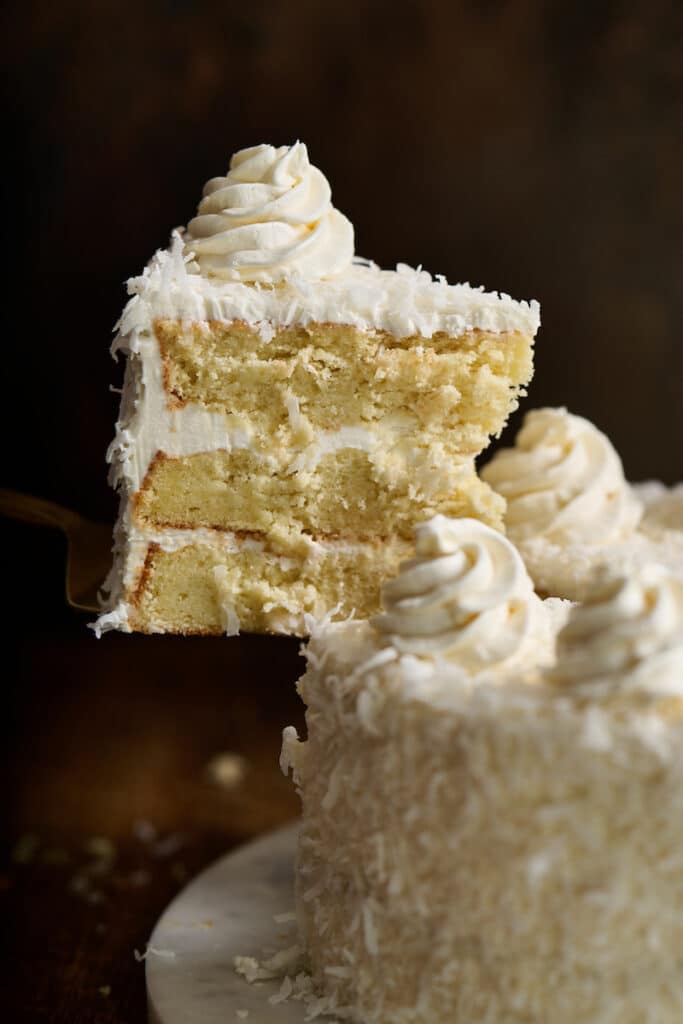 Slice of coconut cake being pulled from the platter.