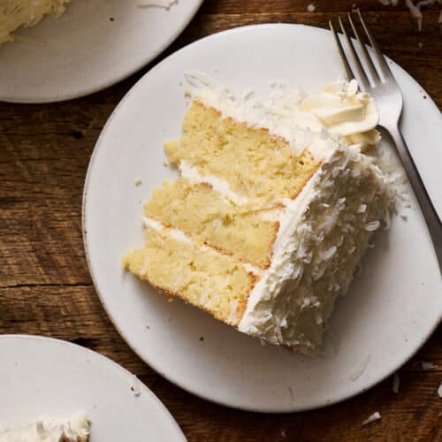 Slice of coconut cake on a white plate.