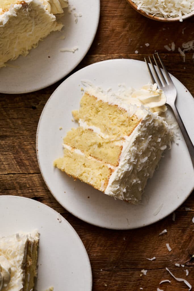 Slice of coconut cake on a white plate.